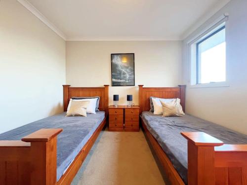 two beds in a bedroom with two windows at Retreat Andrew House in Point Cook