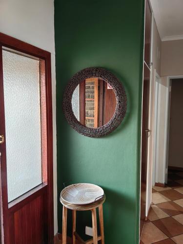 a room with a green wall with a mirror and a stool at Kudus Hide in Richards Bay