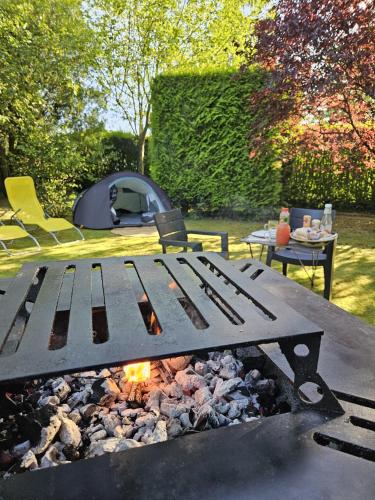 a picnic table with a campfire and a tent at L Escale Nature in Tournai