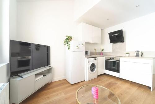 une cuisine blanche avec une table en verre au milieu dans l'établissement F2 Cosy 4 people - 9 min walk from Stade de France, à Saint-Denis