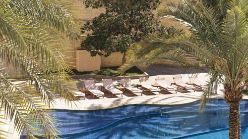 a pool with lounge chairs and a palm tree at InterContinental Amman Jordan by IHG in Amman