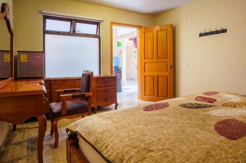 a bedroom with a desk and a bed and a dresser at Tierra Alta Hostal in San Cristóbal de Las Casas