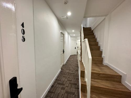 a hallway with a stairway with white walls and wooden floors at The White Den Sukhumvit 44 in Bangkok