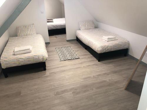 Cette petite chambre comprend 2 lits et un tapis. dans l'établissement Appart Sara-Dieppe, La Perle, à Neuville-lès-Dieppe