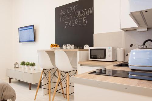 a kitchen with two white stools and a counter at Tesla Boutique Apartments & Rooms in Zagreb