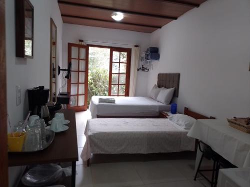 a bedroom with two beds and a table and a window at Loft da Montanha (A 8min do centro) in Nova Friburgo
