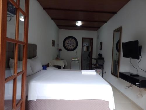 una camera da letto con un letto bianco e uno specchio di Loft da Montanha (A 8min do centro) a Nova Friburgo