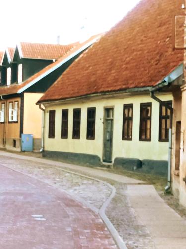 a white building with a brown roof and a street at STĀRĶA APARTAMENTI in Kuldīga