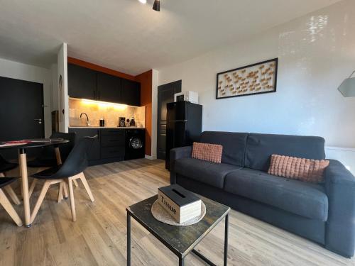 un salon avec un canapé bleu et une cuisine dans l'établissement L'Étape Cosy, Parking Gratuit, à Carcassonne