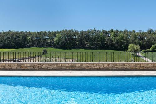 a swimming pool with a fence and blue water at Cal Carulla in L'Astor