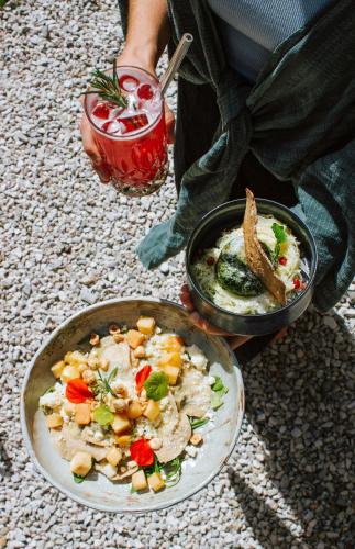a person with a plate of food and a bowl of food at SchönBerg hotel b&b in Rio Bianco