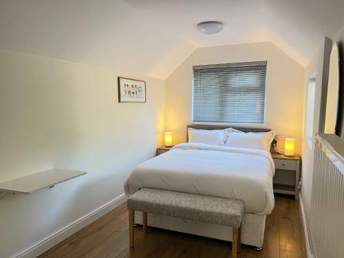 a white bedroom with a bed and a chair at The Cosy Place near centre in Ipswich