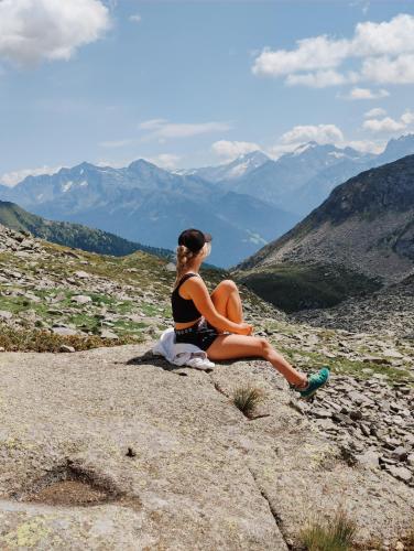 a woman sitting on a rock looking at the mountains at SchönBerg hotel b&b in Rio Bianco