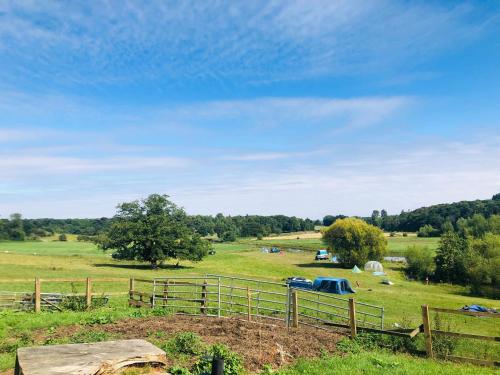 a field with a fence and trees in the distance at Hertford Farm riverside camping firepit bbq in Hertford