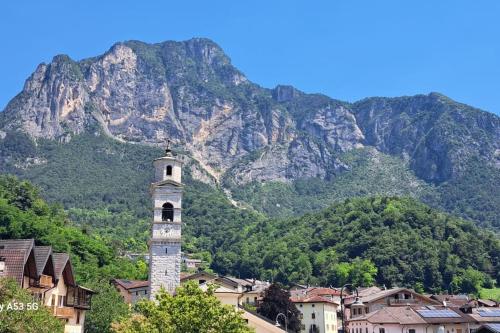 a clock tower with a mountain in the background at Casa del piccolo olivo in Strigno