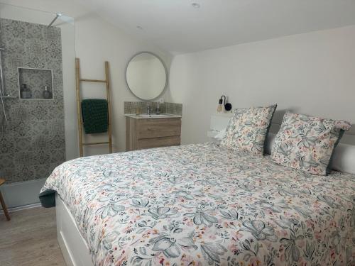 a bedroom with a bed with a floral bedspread and a mirror at ÔTroisChênes - Gîte au calme avec spa privatif in Saint-Astier