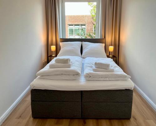 a bed with two pillows and a window in a room at Come2Stay - Pinneberg Zentral in Pinneberg