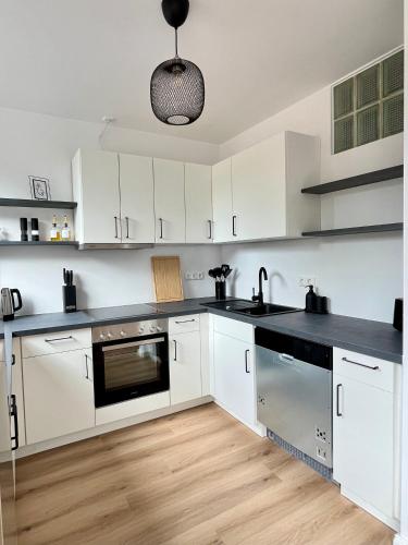 a kitchen with white cabinets and a black counter top at Come2Stay - Pinneberg Zentral in Pinneberg