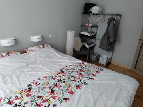 a bed with a white blanket with flowers on it at Located in Ances pagasts Apartments in Ance