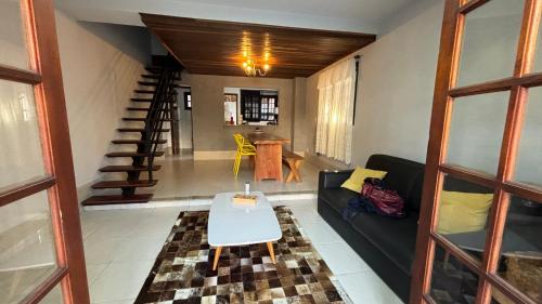 a living room with a black couch and a table at Chalé Benfica - Condominio Chales do Parque in Itatiaia