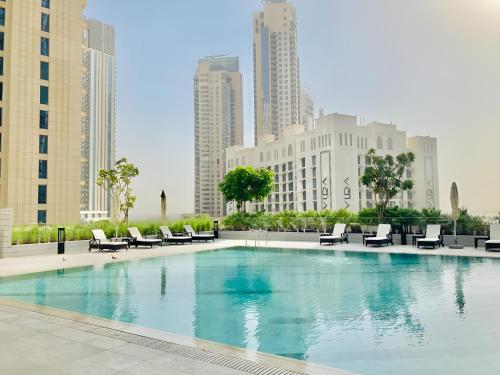 a large swimming pool with chairs and buildings at CitiHome-1BR Large Living Room Ideal for Small Families in Dubai