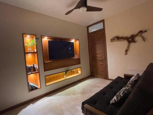 a living room with a couch and a flat screen tv at Villa Yaakun in Tulum