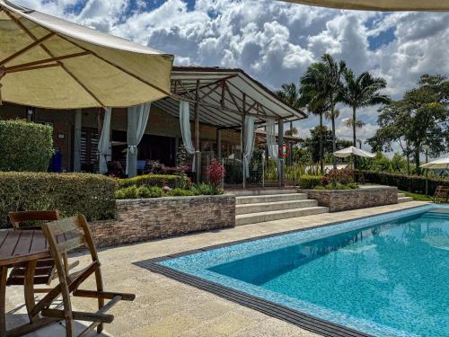 a swimming pool with a table and an umbrella at Finca del Café - Casa Typica in Santa Rosa de Cabal