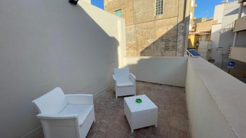 a balcony with two white chairs and a table at Lazzara 19 in Marsala