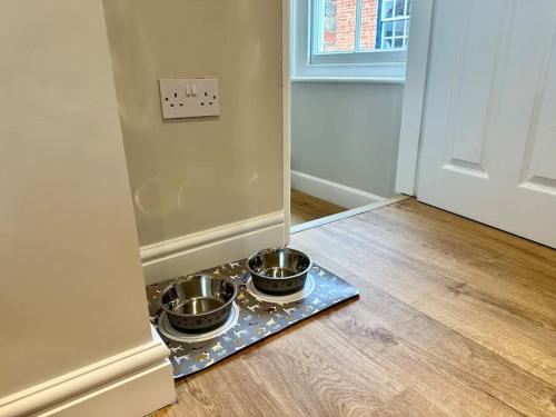 two bowls on a tray on a floor next to a door at The Top Deck, Wells-next-the-Sea in Wells next the Sea