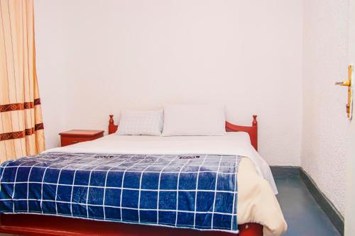 une chambre avec un lit avec une couverture bleue et blanche dans l'établissement Eco Cottage BnB, à Ruhengeri
