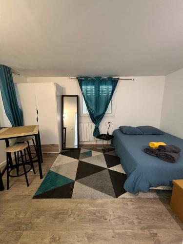 a bedroom with a bed and a desk and a table at Studio Cozy proche aéroport CDG in Claye-Souilly