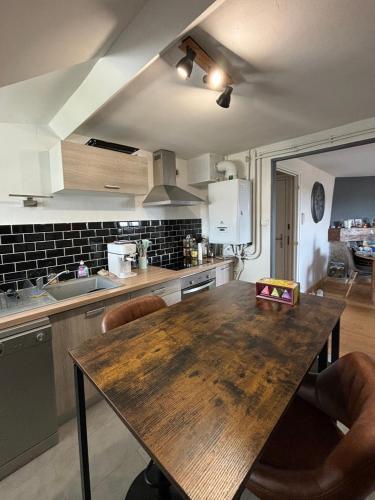 Il comprend une cuisine avec une table et des chaises en bois. dans l'établissement Le cocon, à Aurillac