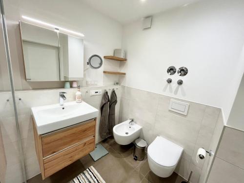 a white bathroom with a sink and a toilet at Lieblingshafen in Heiligenhafen