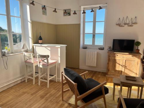 un salon avec une table, des chaises et une télévision dans l'établissement Belle vue sur la mer, à Veules-les-Roses
