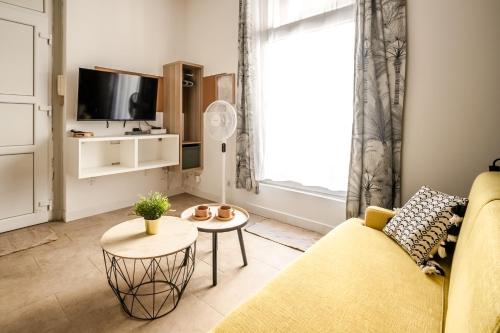 - un salon avec un canapé jaune et une télévision dans l'établissement Studio Hélios Narbona, à Narbonne