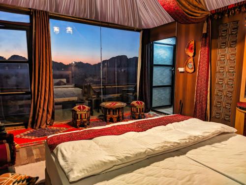 a bedroom with a bed in front of a large window at Wadi Rum Majestic Camp in Wadi Rum