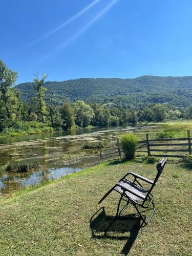 a bench sitting on the grass next to a river at Bed and Breakfast Family Djukic in Šipovo
