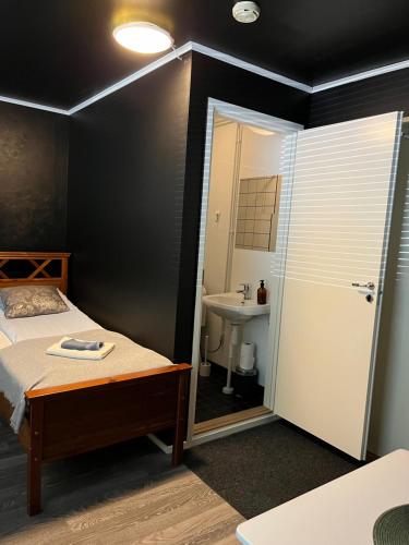 a bedroom with a bed and a bathroom with a sink at Hotelli Keskipiste in Kärsämäki