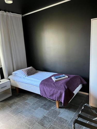 a bedroom with a bed with a purple blanket at Hotelli Keskipiste in Kärsämäki