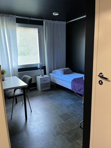 a bedroom with a bed and a desk and a table at Hotelli Keskipiste in Kärsämäki
