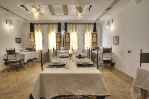 a dining room with tables and chairs and windows at Dar Rihana Dadès in Aït Idaïr