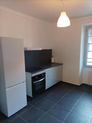Il comprend une cuisine équipée d'un comptoir noir et d'un réfrigérateur blanc. dans l'établissement O'Couvent - Appartement 252 - 1 chambre - 72m2, à Salins-les-Bains