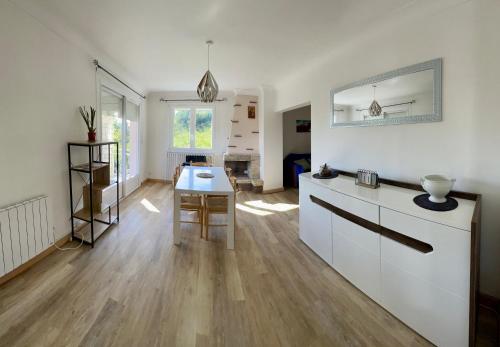 une cuisine avec des armoires blanches et une table dans une pièce dans l'établissement Les Glycines, à Nicole