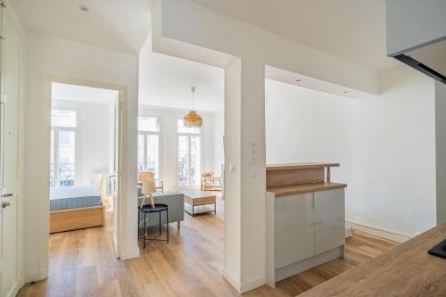 Il comprend une cuisine et un salon avec des murs blancs et du parquet. dans l'établissement Le Castellane coeur centre ville, à Marseille