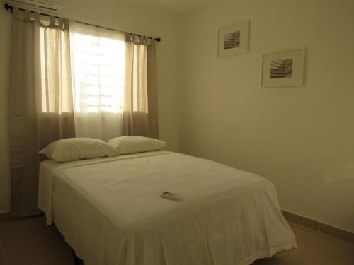 a bedroom with a white bed with a window at Apartamento Acogedor en Santo Domingo Este Ciudad Juan Bosh in La Javilla