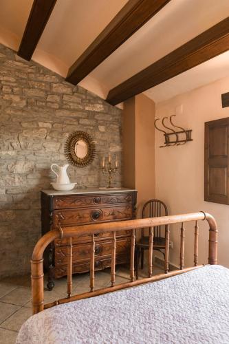 a bedroom with a bed and a stone wall at Cal Carulla in L'Astor
