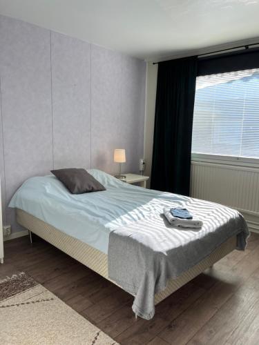 a bedroom with a bed with a blanket and a window at Hotelli Keskipiste in Kärsämäki