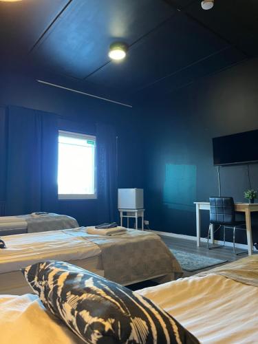 a room with three beds and a blue wall at Hotelli Keskipiste in Kärsämäki