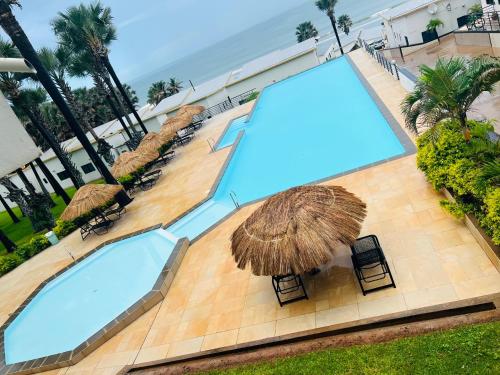 an overhead view of two swimming pools with umbrellas at Relax Oceanfront Suites in Sere Kunda