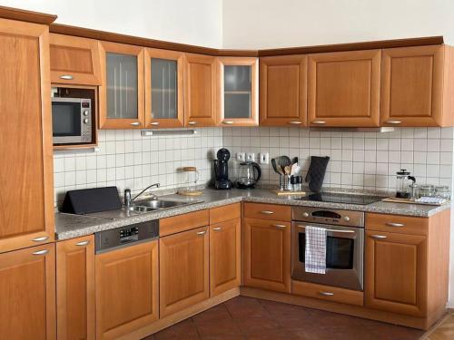 a kitchen with wooden cabinets and stainless steel appliances at Spacious Elegance - A Central Gem in Prague